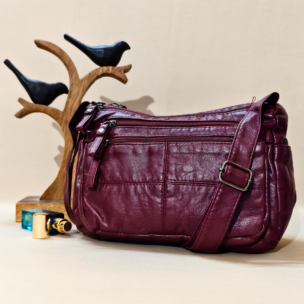 Purple leather handbag on a beige surface with decorative elements.