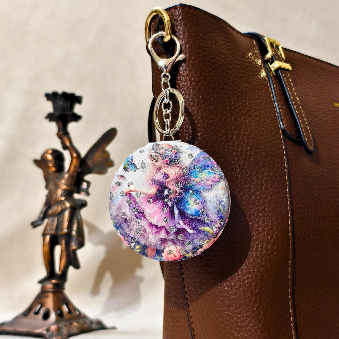 Colorful fairy-themed keychain attached to a brown leather bag with a statue in the background.