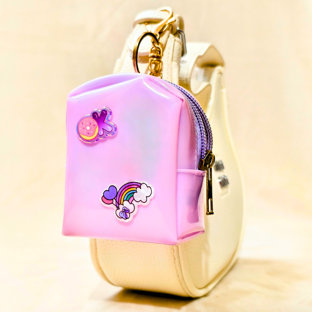 Pink and gold keychain with cartoon character on a beige background