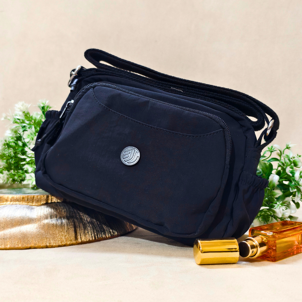 Black crossbody bag on a beige surface with decorative items