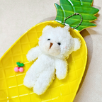 White teddy bear keychain on a yellow pineapple-shaped tray