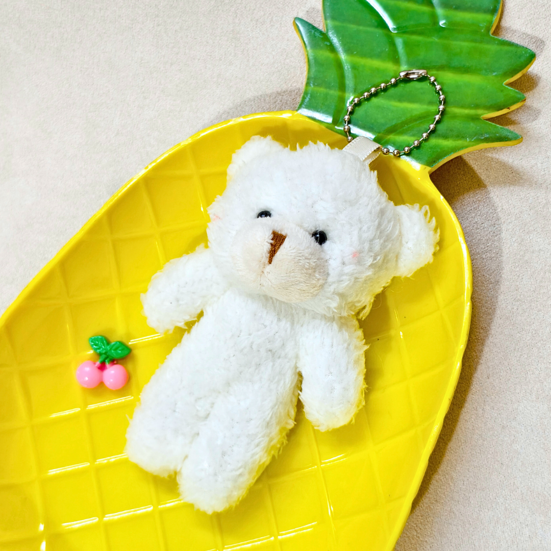 White teddy bear keychain on a yellow pineapple-shaped tray