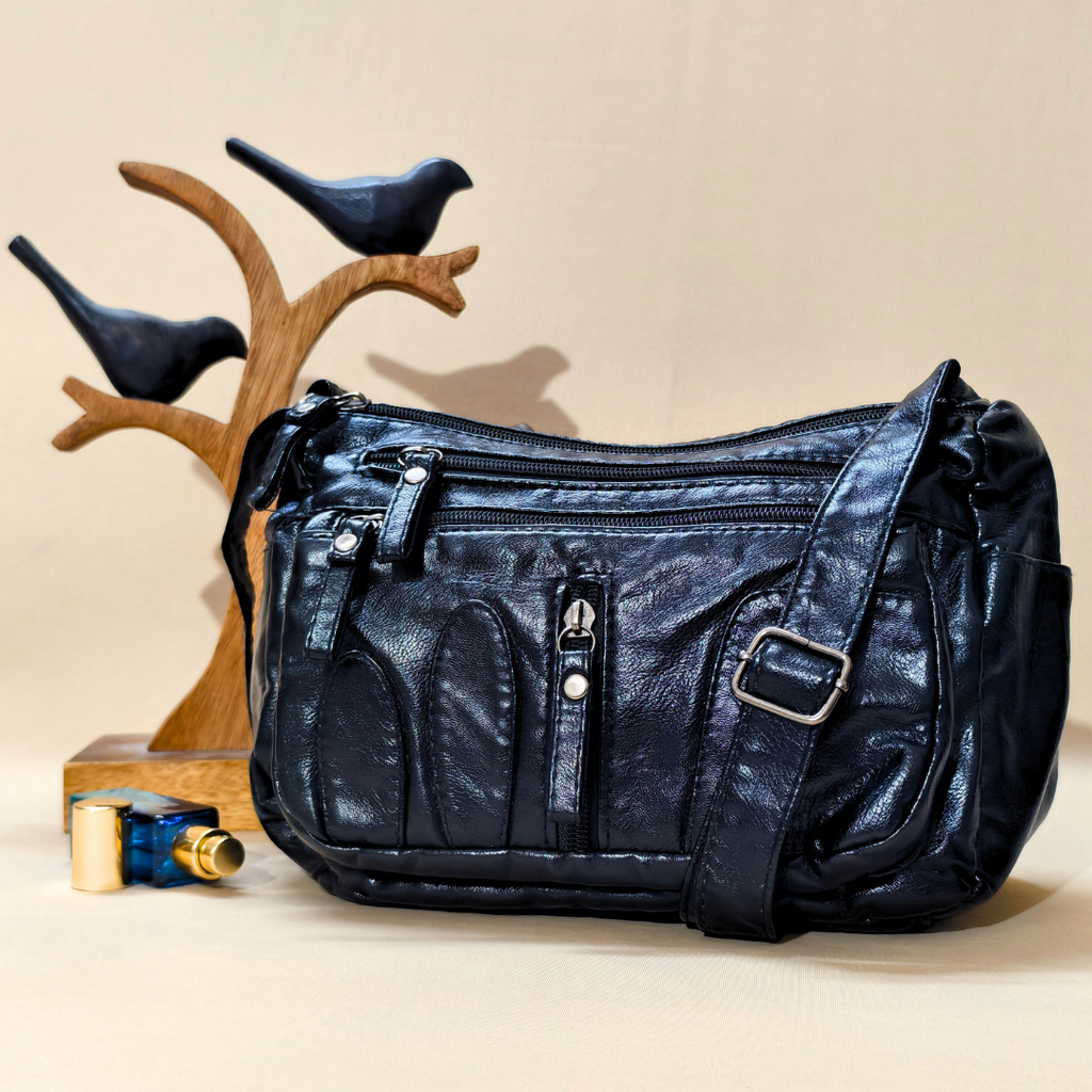Black leather handbag on a beige surface with decorative birds in the background