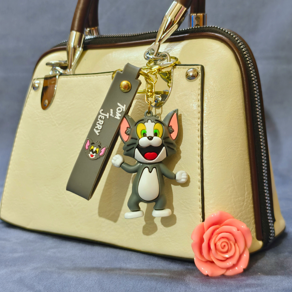 Beige handbag with a cartoon character keychain and a pink rose on a gray background