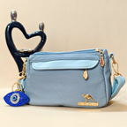 Blue handbag with gold accents and a decorative charm on a beige background