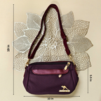 Purple handbag with gold accents on a textured beige background, showing measurements.