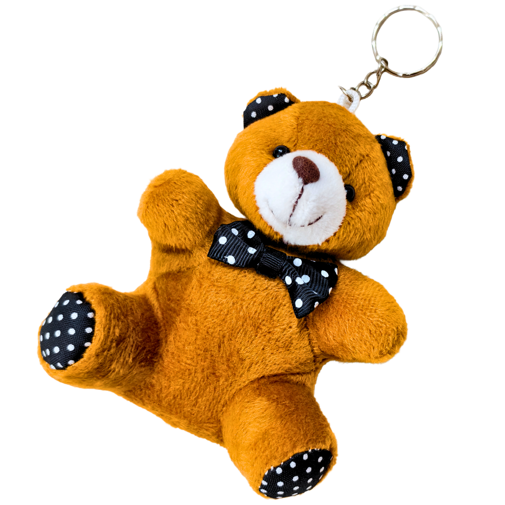A small plush teddy bear keychain in brown with a white snout, black polka-dot bow tie, and black polka-dot ears and paw pads, attached to a silver metal key ring on a plain white background.