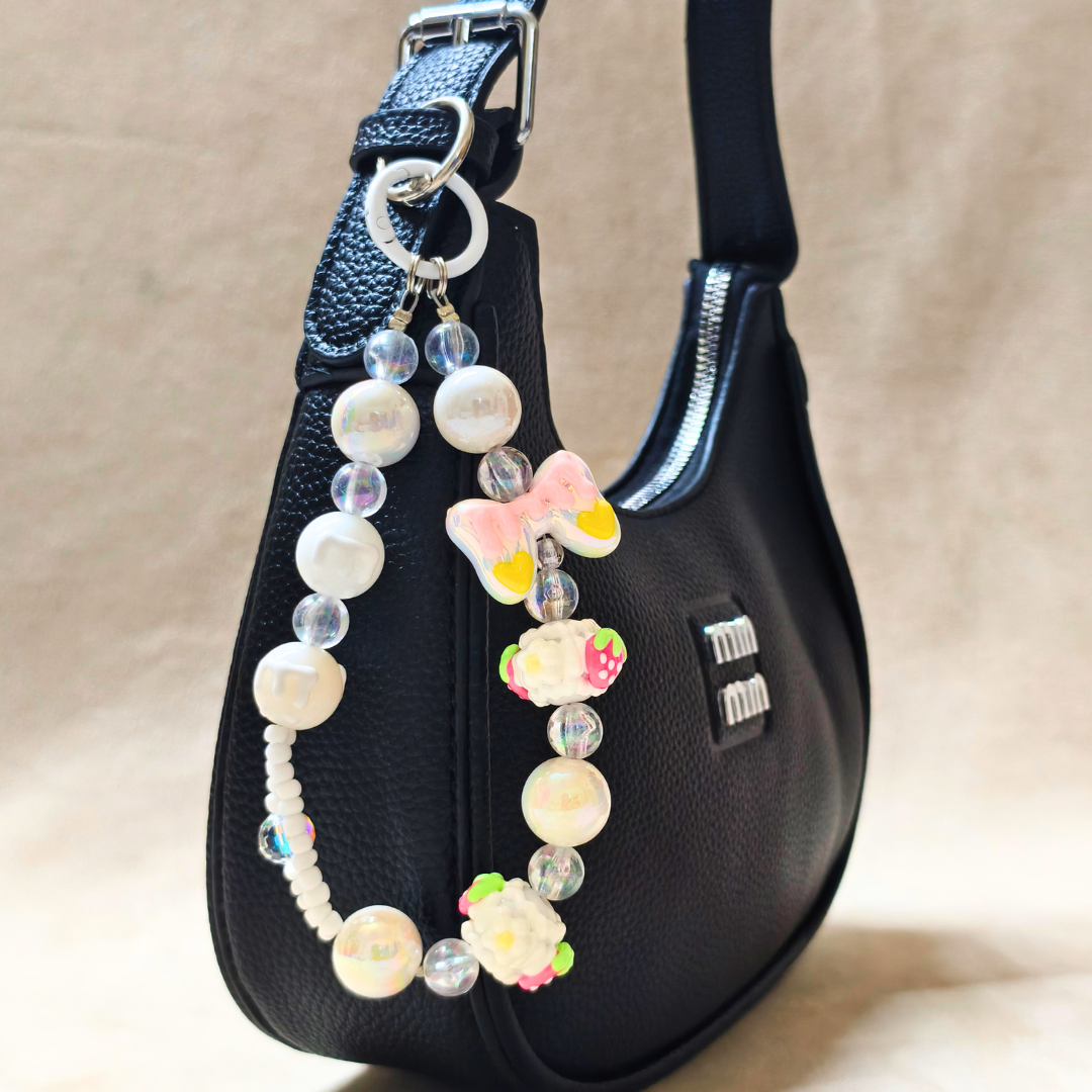 Beaded keychain with floral designs attached to a black handbag.