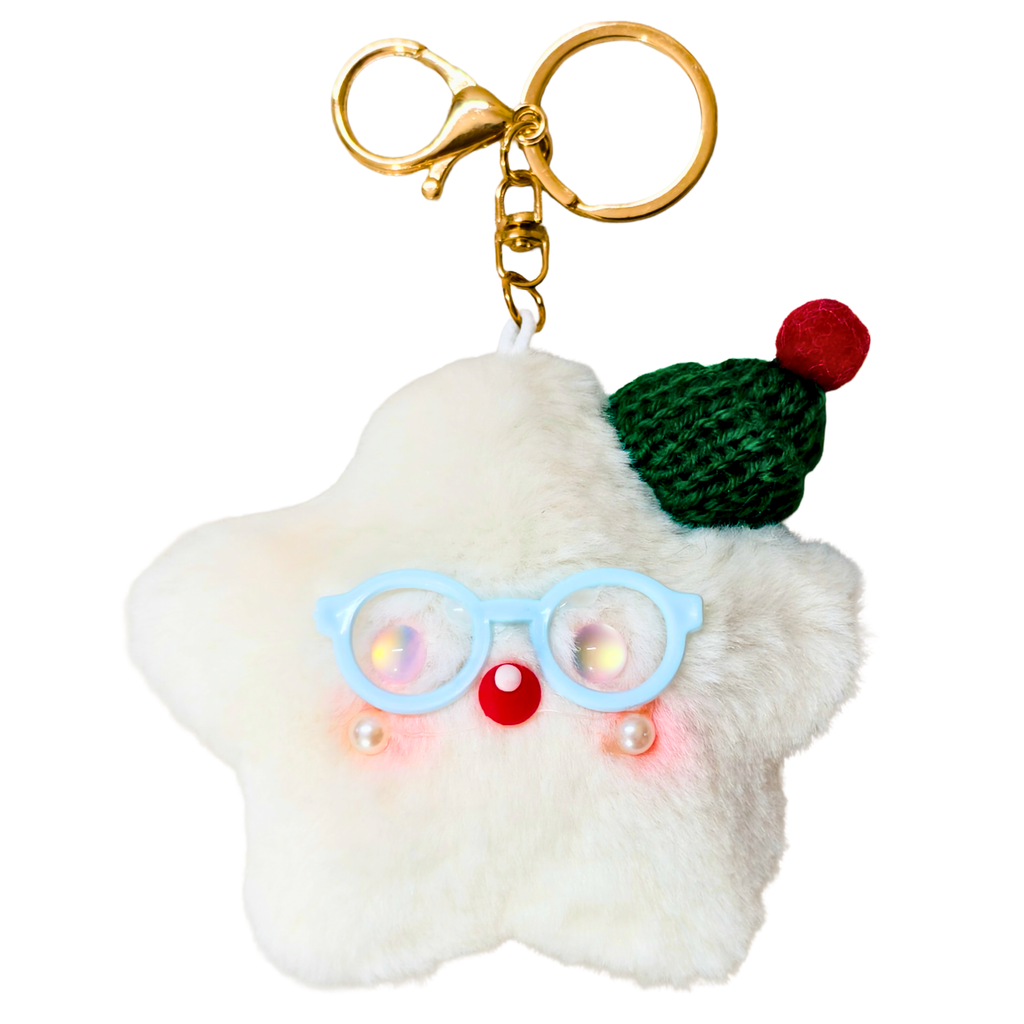 A fluffy white star-shaped keychain charm with a gold clasp, featuring light blue glasses, a red nose, small pearl-like accents, a green knit hat, and a red pom-pom, shown on a plain white background.