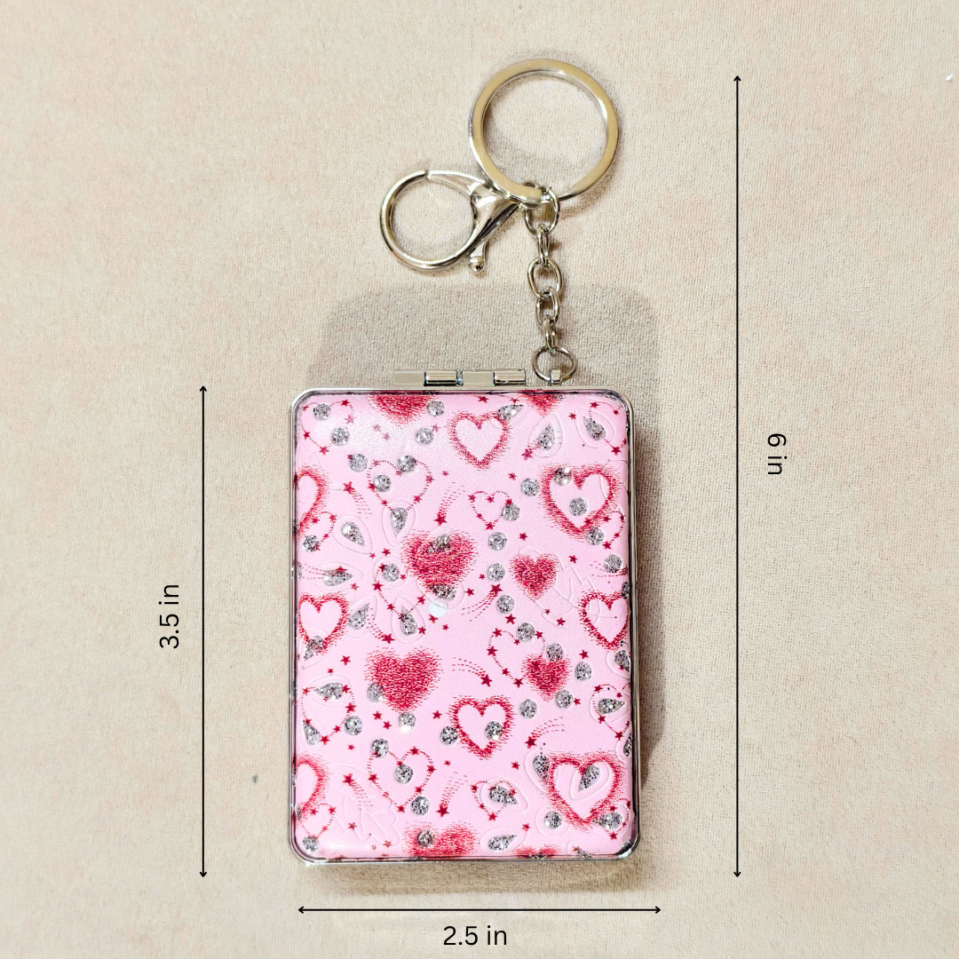 A rectangular compact-style keychain with a pink heart pattern, shown with metal key rings and clasp. Black dimension lines and text indicate measurements of 3.