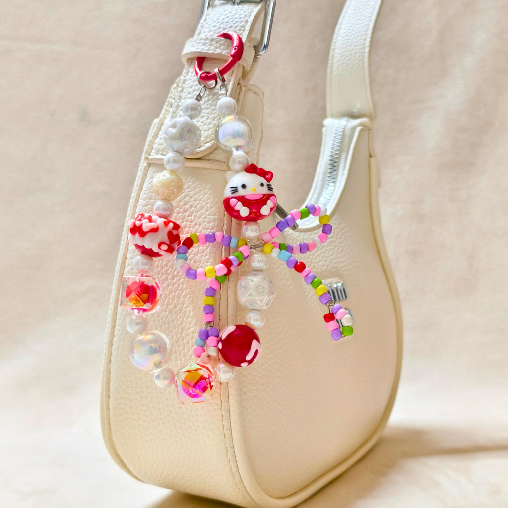 Beaded charm with a character design on a beige handbag.