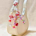 Beaded charm with a character design on a beige handbag.