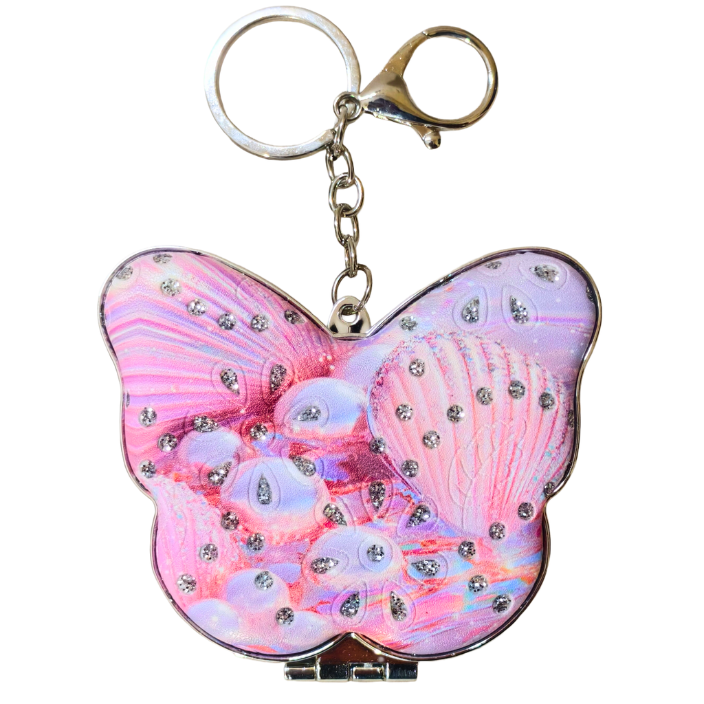 A butterfly-shaped compact mirror with a pink and purple seashell design, embellished with rhinestones, attached to a silver-tone keychain.