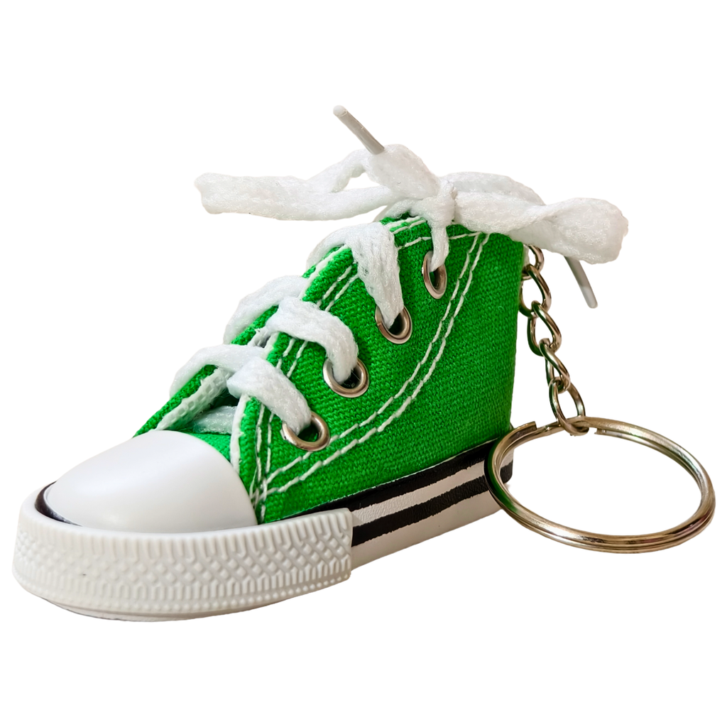 A miniature green canvas high-top sneaker keychain with white laces tied in a bow, a white rubber toe cap, and a gold-tone metal key ring, shown on a plain white background.