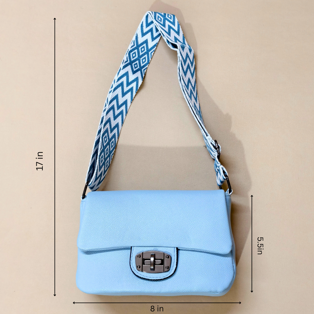 Light blue handbag with a blue and white patterned strap on a beige background