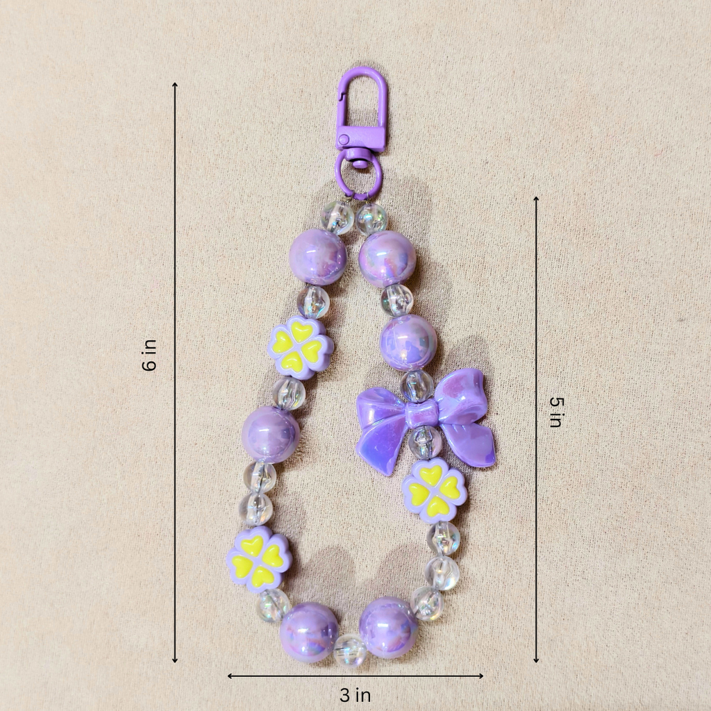 Purple beaded keychain with flowers and a bow, shown with measurements on a beige background.