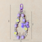 Purple beaded keychain with flowers and a bow, shown with measurements on a beige background.