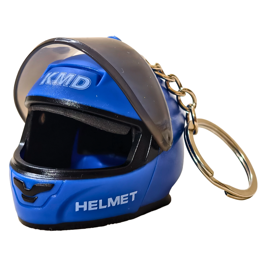 A miniature blue helmet keychain with a clear visor, black interior, white 'KMD' and 'HELMET' text, and a gold-tone metal key ring on a white background.
