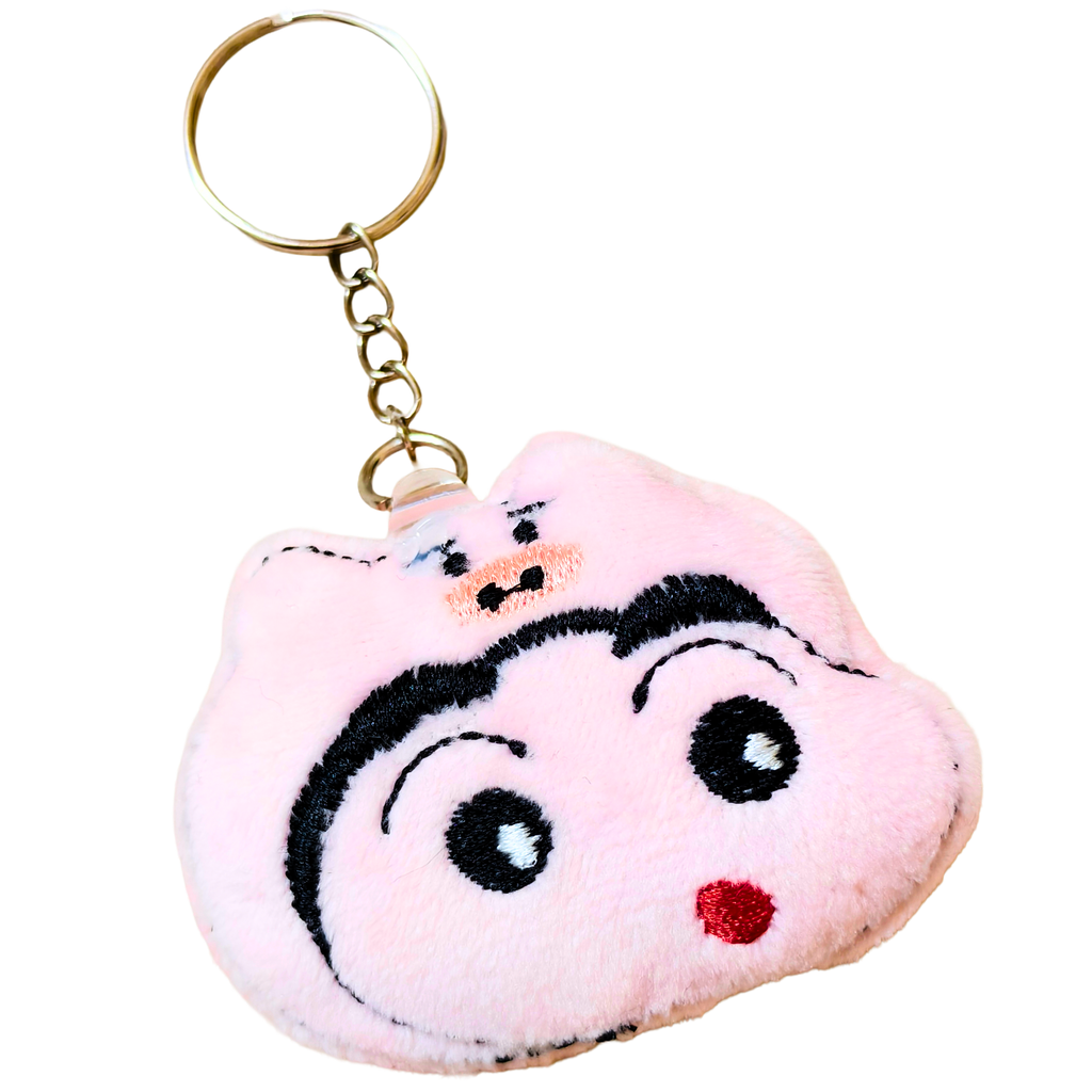 A plush keychain shaped like a cartoon pig face, featuring embroidered black eyebrows, eyes, and mouth details, a small red stitched nose, and a gold metal key ring and chain.