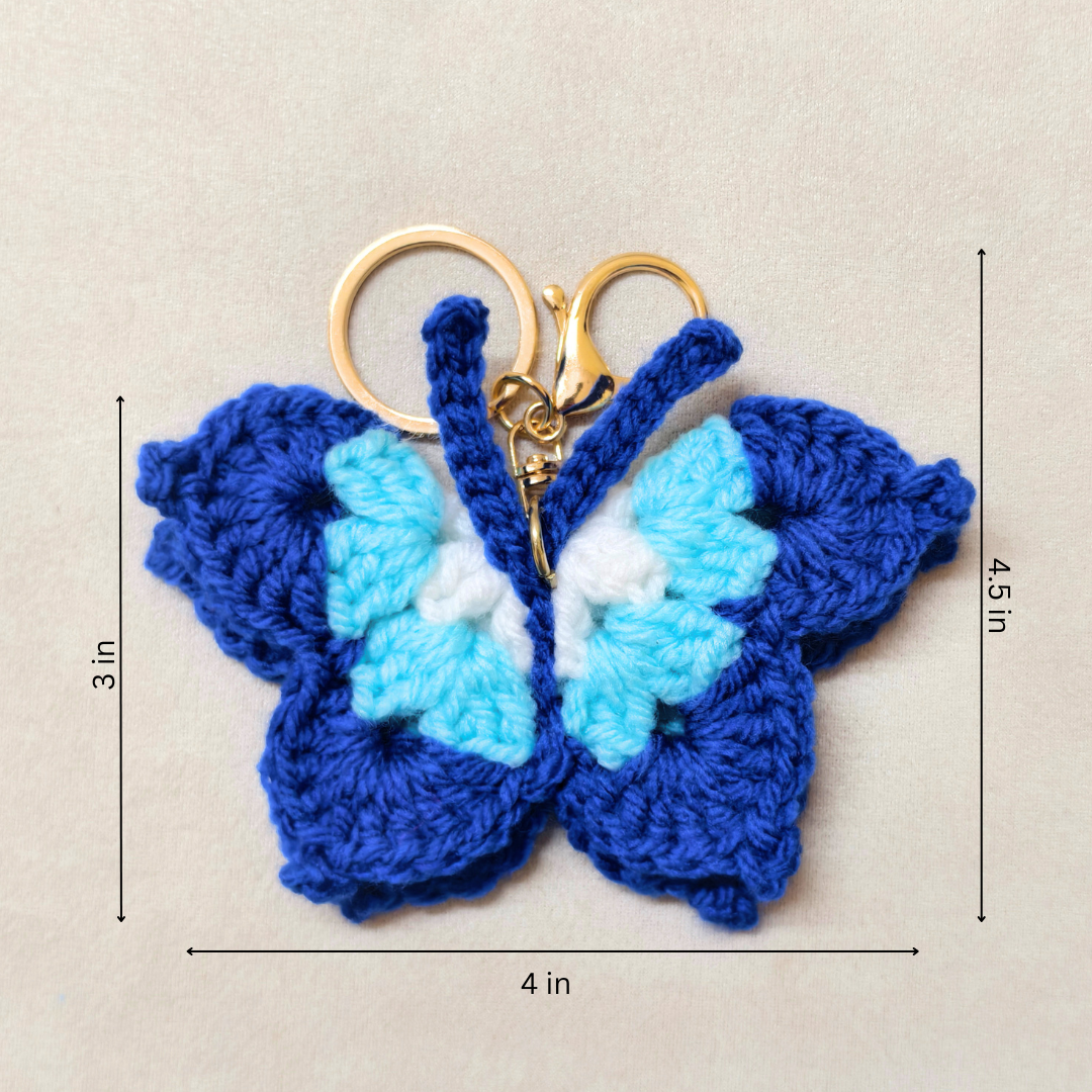 Crocheted butterfly keychain with measurements on a beige background