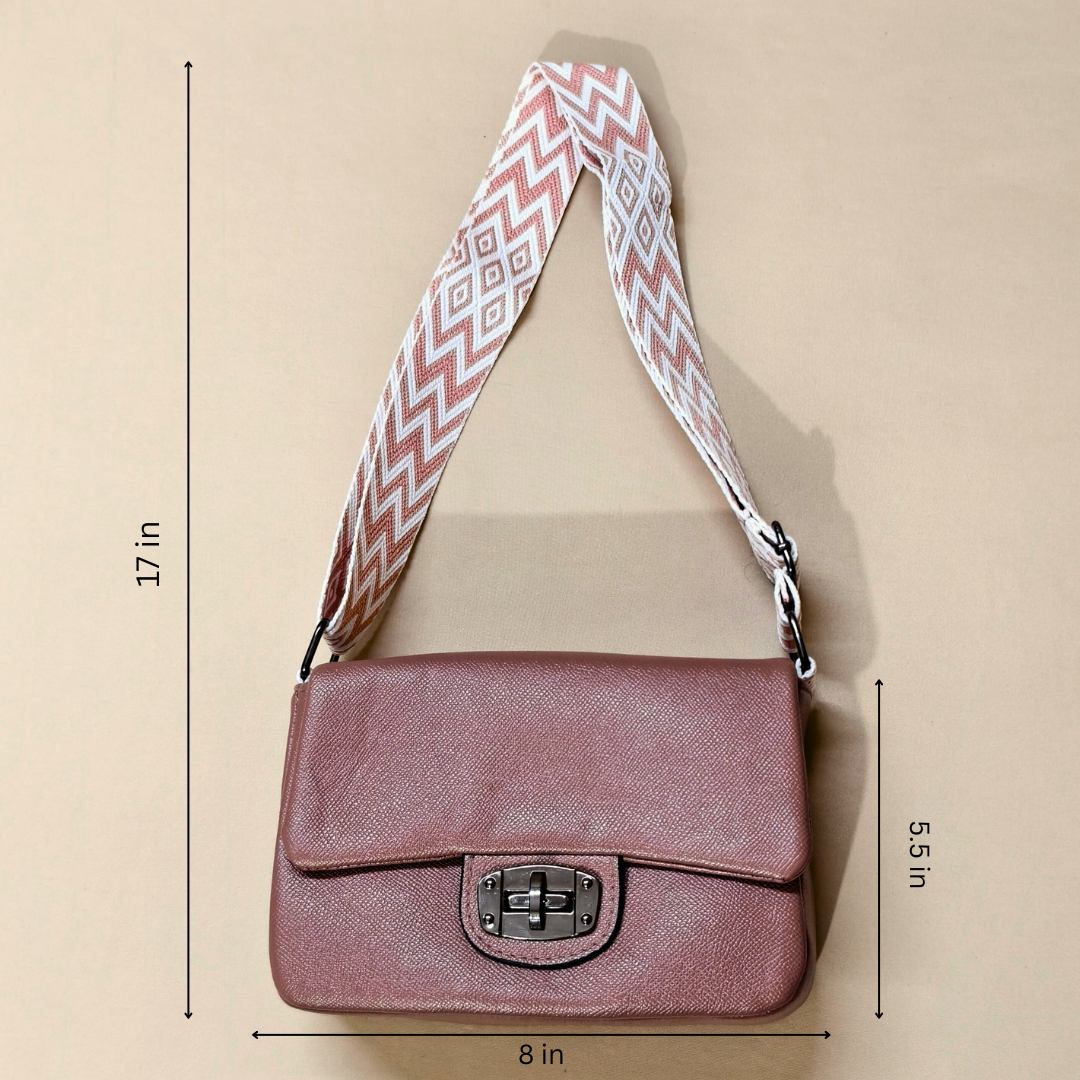 Pink shoulder bag with a patterned strap on a beige background, showing measurements.