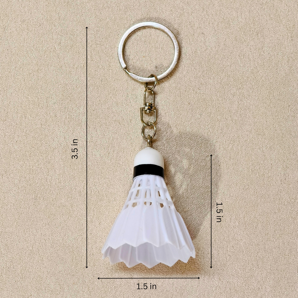 A white plastic shuttlecock keychain with a silver metal split ring and chain, shown on a beige textured background with black dimension lines and text indicating measurements of 3.5 in, 1.