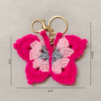 Crocheted butterfly keychain with gold ring and measurements on a beige background
