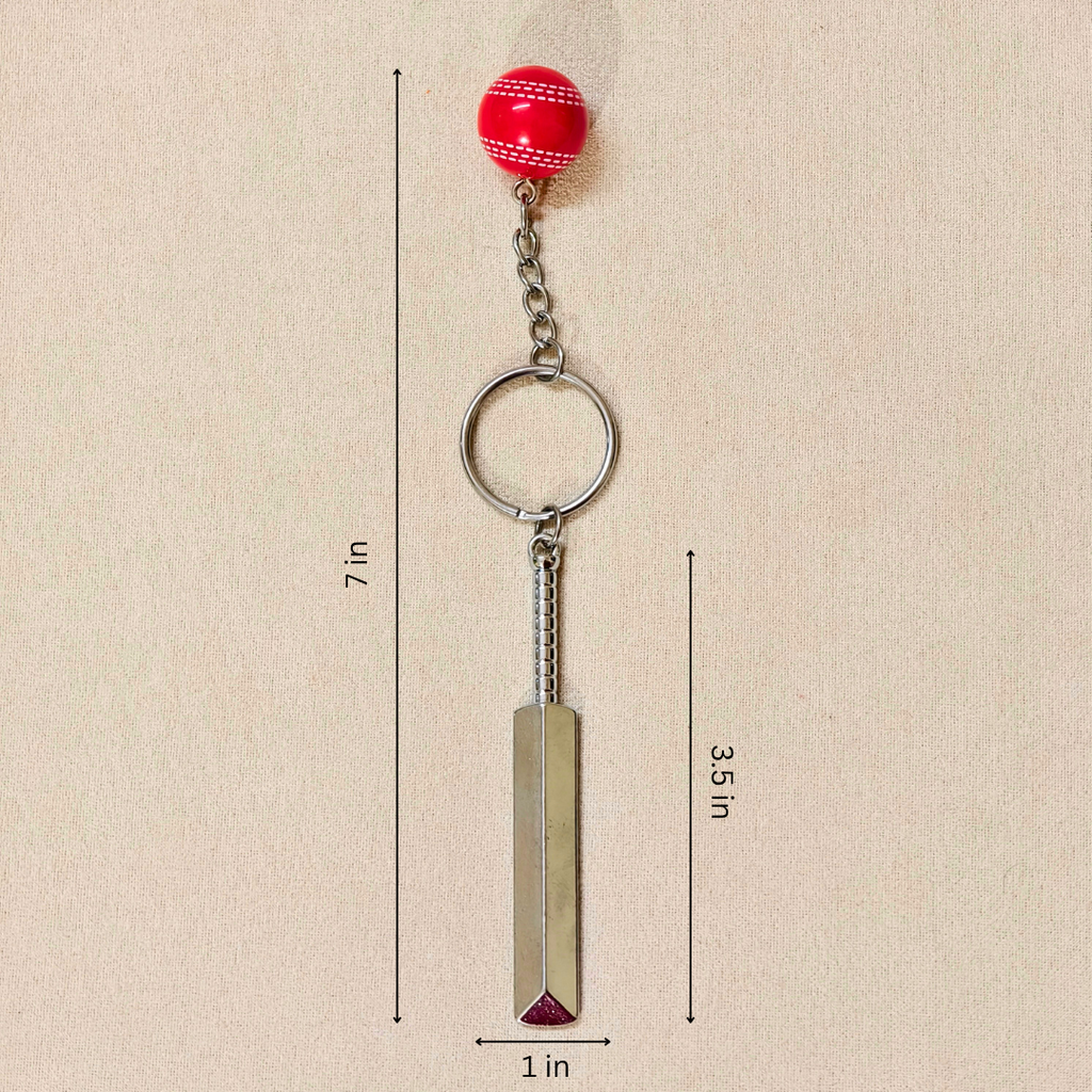 silver metal Cricket Bat and Ball  keychain with a small Cricket Ball attached, showing measurements against a plain beige background.


