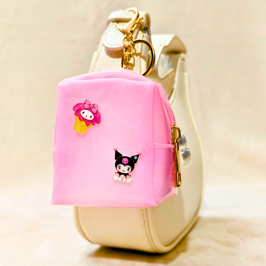 Pink keychain case with cartoon characters attached to a beige handbag.