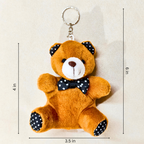 A plush teddy bear keychain in brown with a white snout, black polka-dot ears and bow tie, and black polka-dot paw pads, shown on a light beige background with dimension lines indicating 3.5 in width, 4 in height, and 6 in overall size.