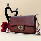 Brown leather handbag with a decorative strap on a beige background