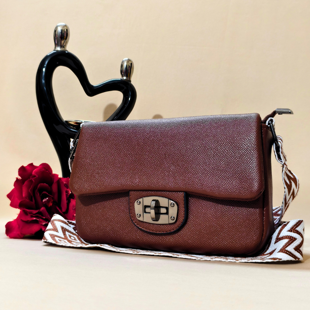 Brown leather handbag with a decorative strap on a beige background
