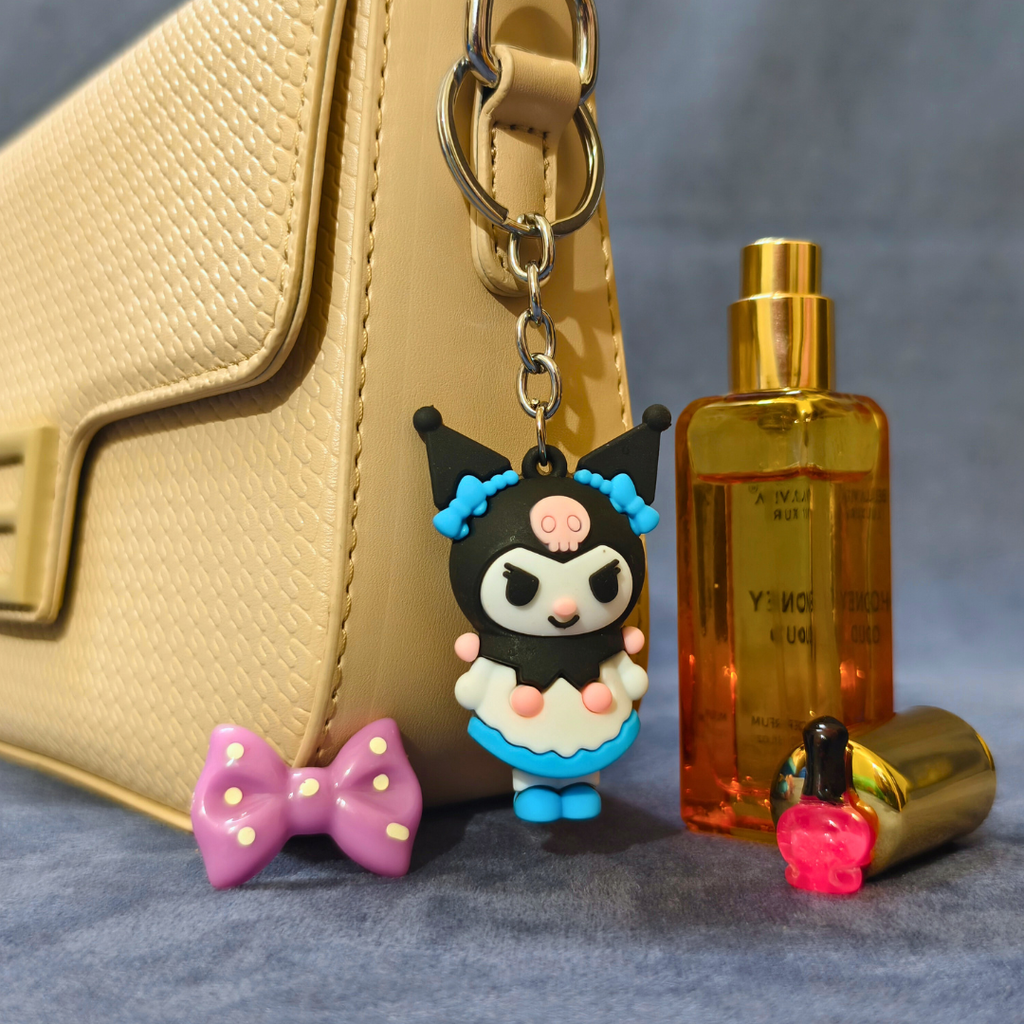 Keychain with cartoon character, bow, perfume bottle, and nail polish on a textured surface.