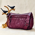 Purple leather handbag with multiple zippers on a neutral background