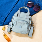 Gray backpack with sunglasses and a bottle on a blue fabric background
