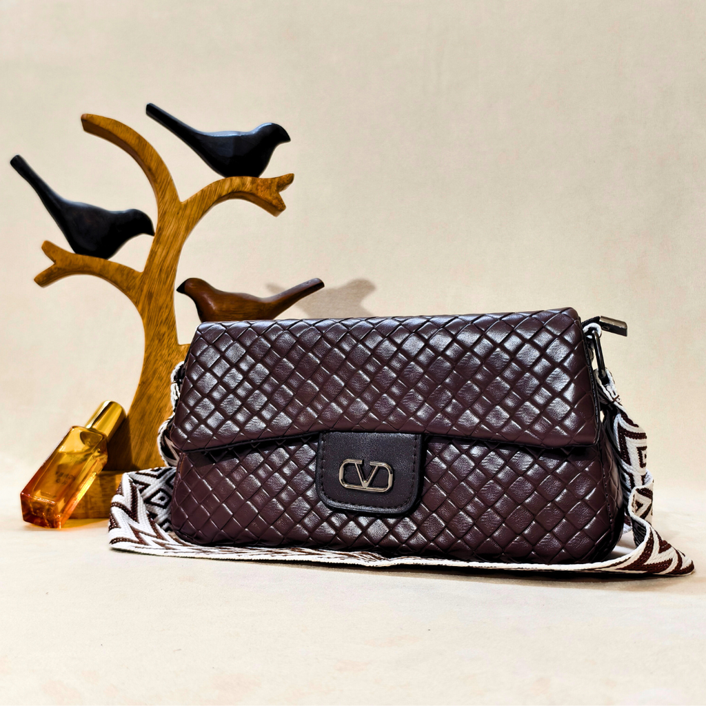 Quilted brown handbag on a decorative stand with birds and a crystal.