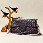 Quilted brown handbag on a decorative stand with birds and a crystal.