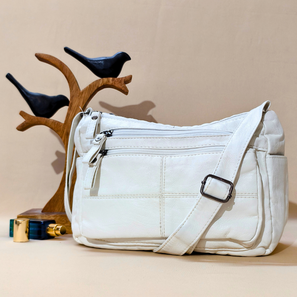 White handbag on a beige surface with decorative birds and a wooden stand in the background.