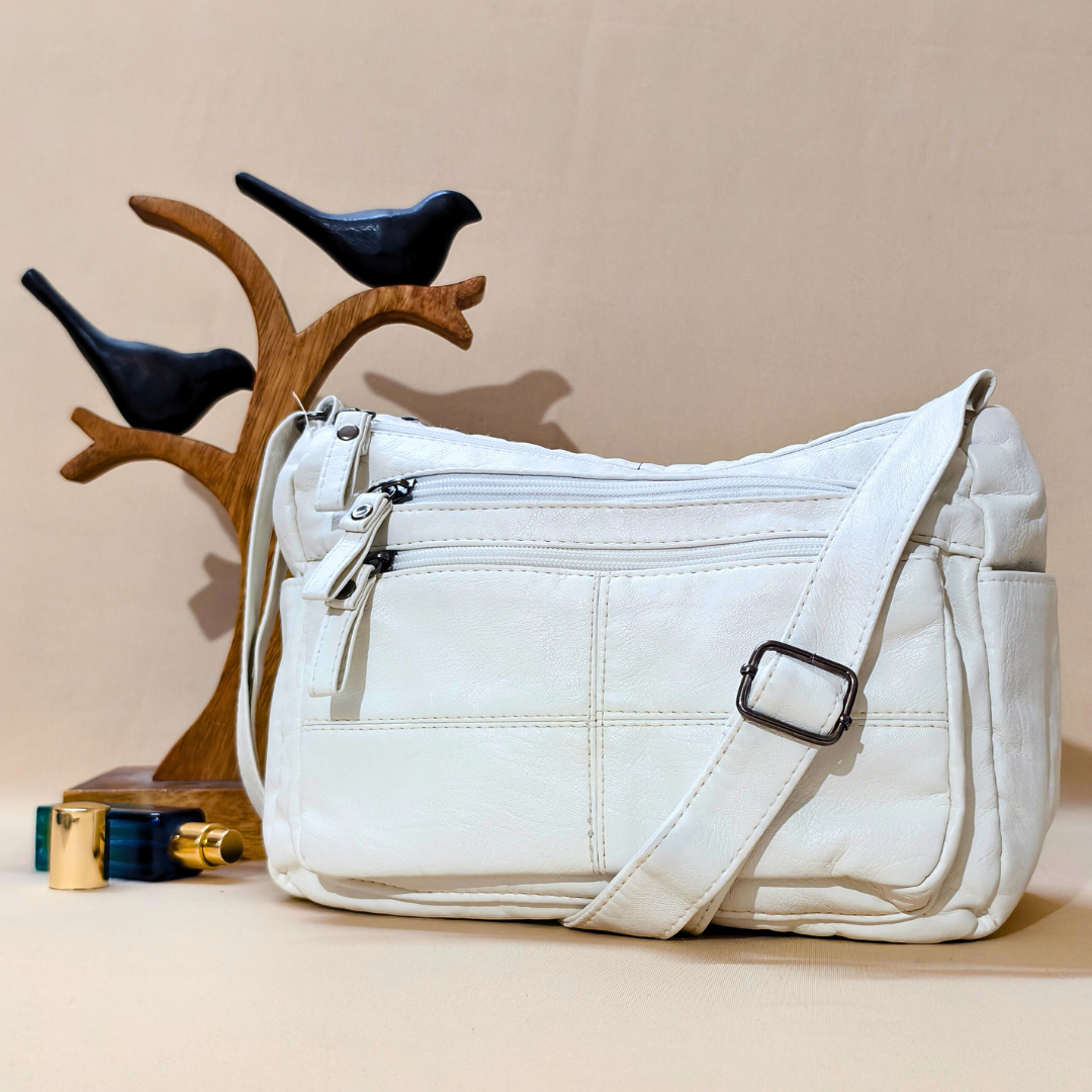 White handbag on a beige surface with decorative birds and a wooden stand in the background.