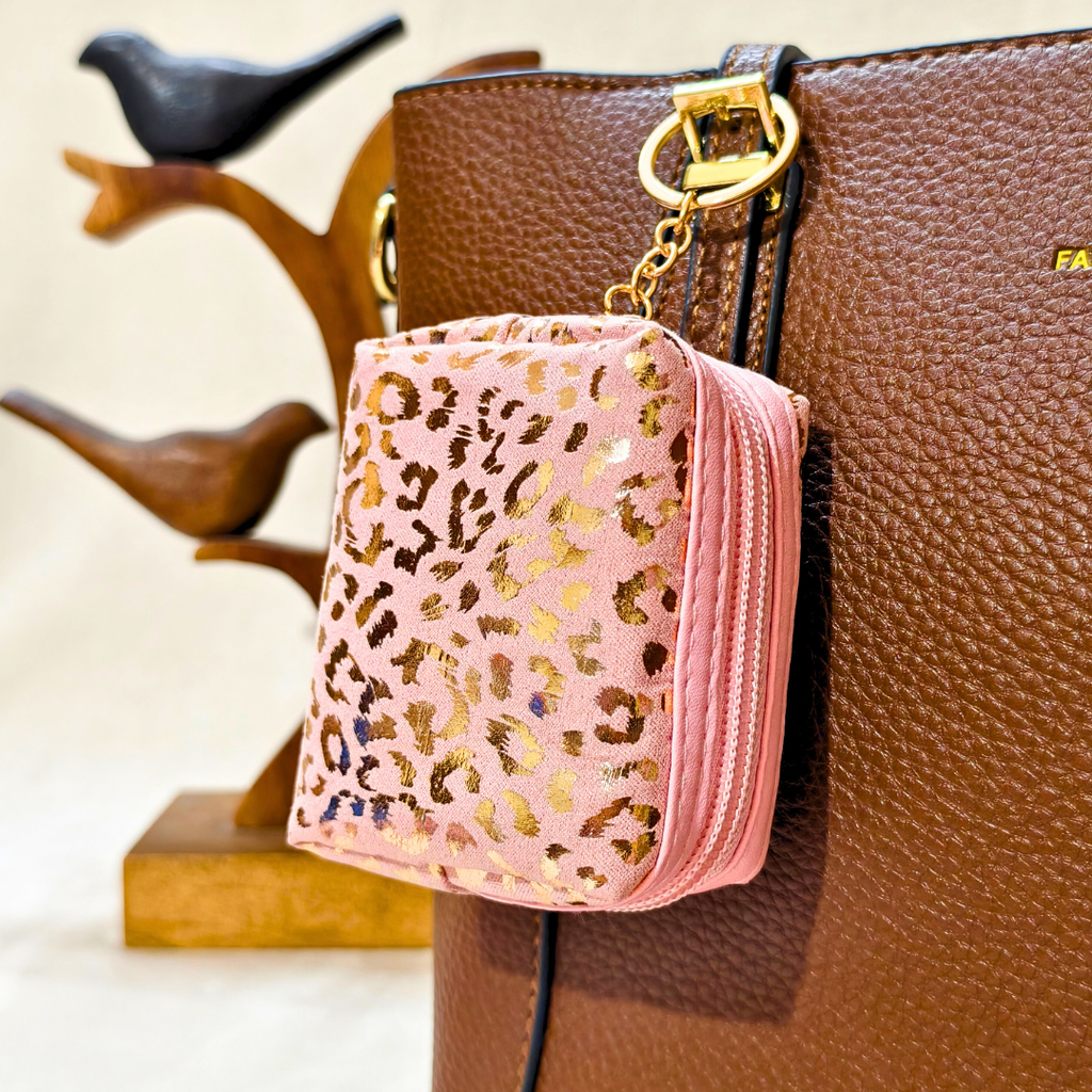 Pink leopard print pouch attached to a brown handbag with decorative elements.