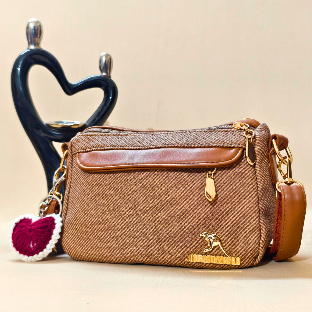 Brown handbag with gold accents and a heart-shaped keychain on a beige background