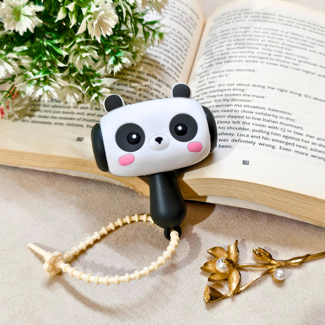 Panda-shaped book mark on an open book with flowers and a gold brooch.