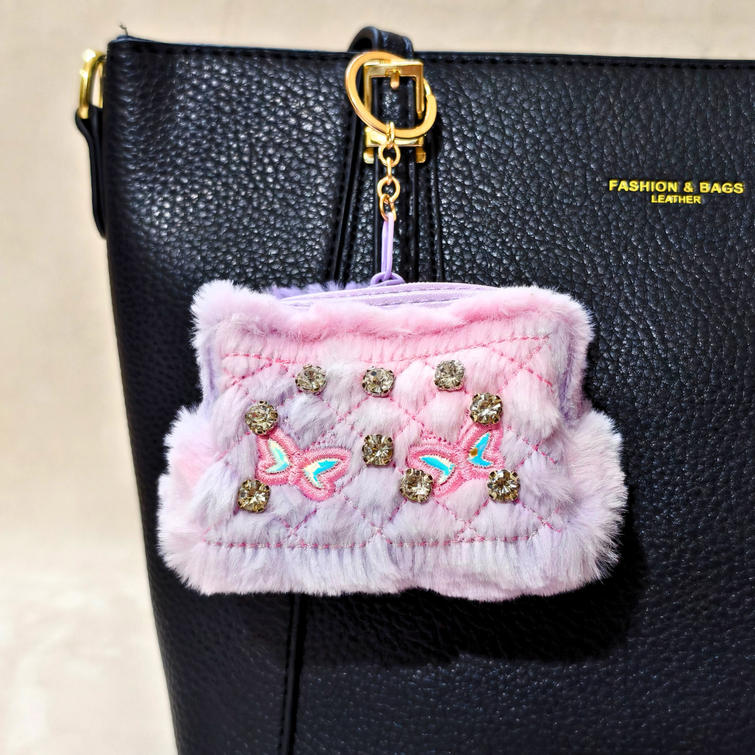 Pink textured pouch with decorative elements attached to a black bag.