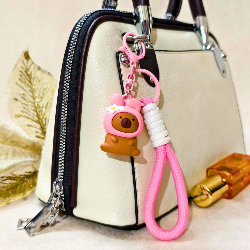 Pink keychain with bear design attached to a handbag
