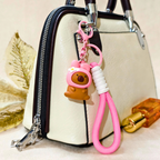 Pink keychain with bear design attached to a handbag