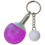 A novelty table tennis keychain featuring a miniature purple and silver paddle with a small white ball charm attached by a silver chain and key ring, shown against a plain white background.