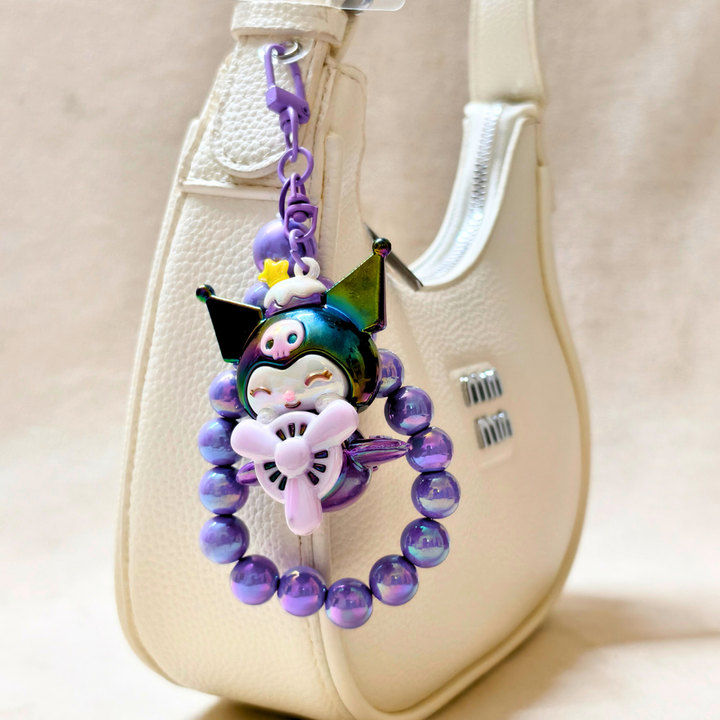 Colorful keychain with a character design attached to a beige bag.