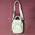 Beige crossbody bag with measurements on a maroon background