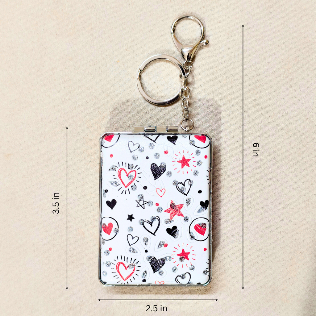 A small rectangular keychain wallet with a white background and a heart-and-star pattern, shown with metal key rings and chain. Black and red heart illustrations, plus measurement lines and labels indicating 3.