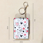A small rectangular keychain wallet with a white background and a heart-and-star pattern, shown with metal key rings and chain. Black and red heart illustrations, plus measurement lines and labels indicating 3.
